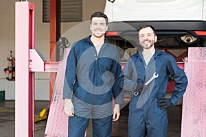 Car Mechanics In Coveralls Standing In Garage