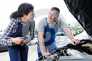 car mechanics filling up reservoir car outside