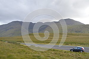 Car in the Middle of a National Road with Vegetation and Mountains in Ireland