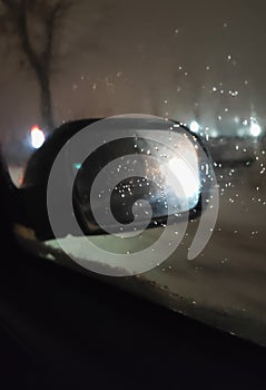 car mirror through glass with drops in the dark