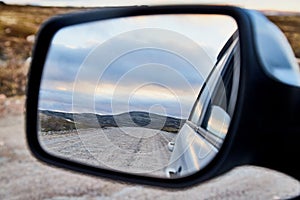 Car Mirror and reflection of the road and sky in it