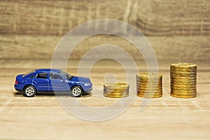 Car model and coin on a wooden table as a concept of buying or renting a car