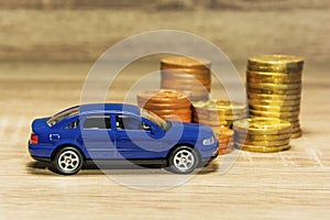 Car model and coin on a wooden table as a concept of buying or renting a car