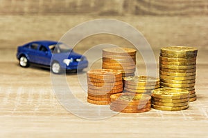 Car model and coin on a wooden table as a concept of buying or renting a car