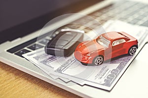 Car model, money and Notebook on wooden desk. shopping online and car payment by using laptop