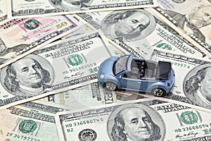 Car model on pile of US dollar banknotes