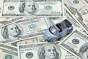 Car model on pile of US dollar banknotes