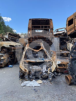 Car morgue. Civilian vehicles after the fire. Rusty pile of metal. Auto in Irpen.