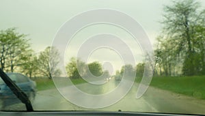 The car moves along the road during the rain and removes the droplets from the windshield