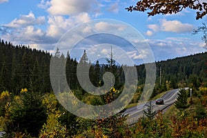 The car moves along a winding asphalt road among the mountains.