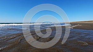 The car moves on a summer day along the sandy sea beach, crosses the rivers and white foam from the waves. Tourists