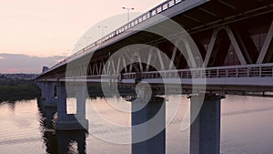 Car moving on bridge over mirror city river. Drone view car traffic on bridge on sunset background