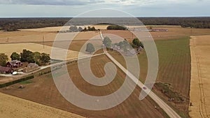 Car moving on countryside rural road among cereal wheat fields and farmhouses