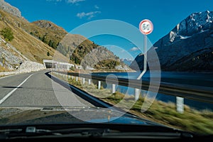 Car moving fast with speed limit violation on a twisty road with a rocky landscape.