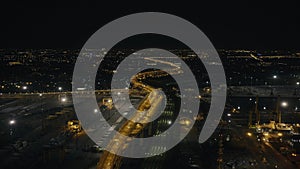 Car moving on night bridge past ships in sea port in modern city of the future