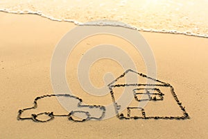 Car is near the house drawn by hand on a sandy sea beach.