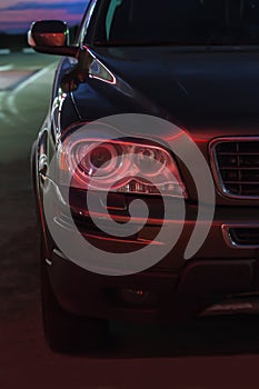 Car on a night road illuminated by a red traffic light