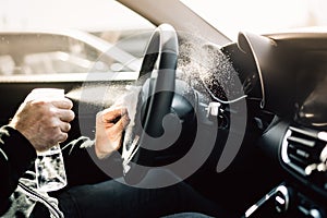 Car owner disinfecting vehicle with alcohol based sanitizing solution spray.Touched surfaces sanitation.Coronavirus COVID-19 photo