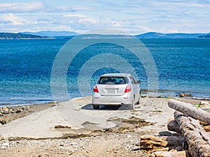 Car parked on the beach, passengers overlooking the water on a s