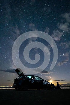 Car parked on a beach under a starry sky