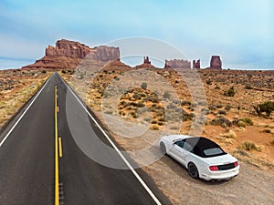 Car parked on the desert asphalt road in Monument Valley in Arizona. USA West coast travel destination concept