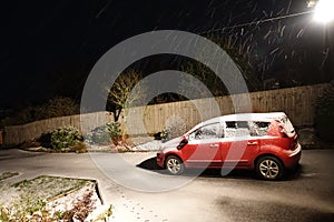 Car parked on driveway at night covered in snow. Winter scene