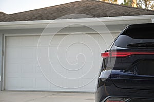 Car parked in front of wide garage double door on concrete driveway of new modern american house