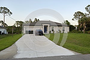 Car parked in front of wide garage double door on concrete driveway of new modern american house