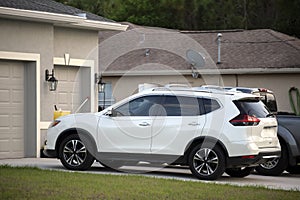 Car parked in front of wide garage double door on concrete driveway of new modern american house