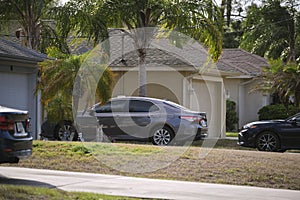 Car parked in front of wide garage double door on concrete driveway of new modern american house