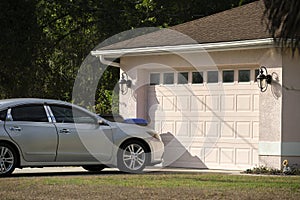 Car parked in front of wide garage double door on concrete driveway of new modern american house