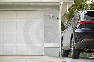 Car parked in front of wide garage double door on concrete driveway of new modern american house