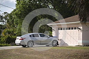 Car parked in front of wide garage double door on concrete driveway of new modern american house