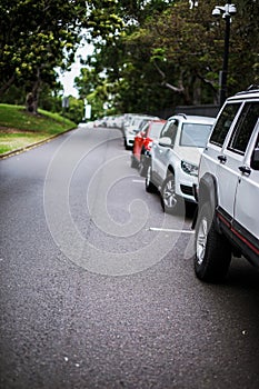 Car parked neatly inside an outdoor parking lot under the tree shade at large public parking