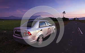 Car parked on roadside at sunset in a rural area