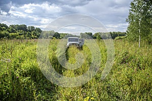 The car is parked in the tall grass. Car  in the middle of wide field