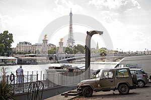 Car parking, barge and Alexander the Third Bridge on the background of the Eiffel Tower in Paris