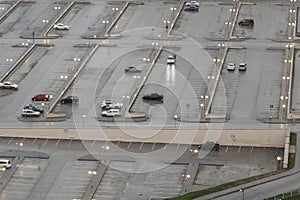 Car parking top view with a lot of marked places near the business center in the evening during the rain with cars with headlights