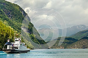 Car and passenger ferry crossing the fjord with mountain landscape in the background, Tafjord, More og Romsdal county, Norway.