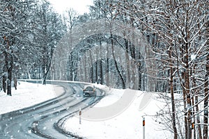 Car passing on a road with snow slush and snow fall