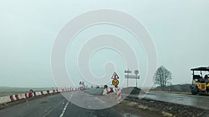 Car point of view driving past repair roadworks, heavy plant machinery in use, speed restrictions apply. Minsk, Belarus