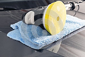 Car polish concept. Buffing and polishing car. Car detailing. Polisher and microfiber cloth on the car. Tools for polishing