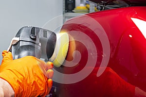 Car polish wax worker hands applying protective tape before polishing. Buffing and polishing car. Car detailing. Man holds a polis