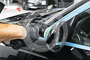 Car polish wax worker hands applying protective tape before polishing. Buffing and polishing car. Car detailing. Man holds a polis