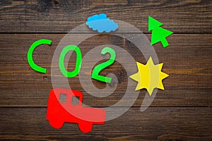 Car pollutes the environment by carbon dioxide. Car, environment and CO2 cutout on dark wooden background top view copy