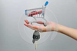 Car purchase concept. Red toy car and car keys in metal shopping cart