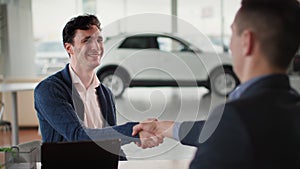 car purchase, happy new vehicle owner taking auto keys from sales manager sitting at table in automobile center