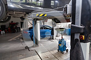 Car raised on a lift for repairing the chassis and engine in a vehicle repair shop. Auto service industry and maintenance