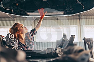 Car reapir. Young red-headed girl, auto mechanic working at auto service station using different work tools. Gender