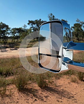 Car Rear View Mirror Of Caravan Towed Across A Dirt Road